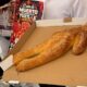 Por cuarta ocasión prepararán el pan de muerto más grande de Los Tuxtlas; medirá más de 10 metros  Cinco panaderías participarán en su elaboración y será repartido gratuitamente el próximo 1 de noviembre en Catemaco, Veracruz.  Enrique Burgos  Con un pan de muerto de más de 10 metros de longitud, Catemaco celebrará el Día de Muertos con la cuarta edición de esta actividad, que reúne a panaderos, artesanos y comerciantes locales para promover las tradiciones y el turismo en la región de Los Tuxtlas.  La elaboración estará a cargo de integrantes de cinco panaderías, mencionó  Antonio Utrera, de la Panadería Artesanal “Don Toño”.  “Bueno, aproximadamente yo le calculo unos más de diez metros, un poquito más de diez metros, y sí se va a llevar más de 200 kilos de harina; cerca de 800, a más de 900 huevos, más leche, azúcar y todo lo que se le pone”, precisó.  Los panaderos señalaron que la elaboración representa un reto por las dimensiones de la pieza, que requiere del trabajo coordinado de varios participantes.  Isidro Hernández, de la panadería “El Trigo de Oro”, explicó que calculan entre dos y tres horas para la preparación y un tiempo similar para darle forma al pan, por lo que el proceso podría extenderse hasta seis horas.  La actividad se realizará el domingo 1 de noviembre en la plazuela de la Virgen del Carmen, ubicada sobre el malecón de Catemaco, donde a la 1:00 de la tarde se llevará a cabo la bendición del pan por parte del padre Santos Abonsa, para posteriormente repartirlo de manera gratuita entre los asistentes.  “El pan es gratis para todos y va a haber chocolate, atole y café; yo creo que hasta ahorita vamos muy bien”, expresó Don Isidro.  Además de la elaboración del pan, el programa contempla una muestra artesanal con productos representativos de Los Tuxtlas, que permanecerá abierta de 9:00 de la mañana a 5:30 de la tarde, así como la participación de distintos negocios locales.  Entre ellos se encuentra la Florería Luimar, que por segundo año consecutivo participará en la celebración con la instalación de un arco floral de aproximadamente nueve metros de ancho, que servirá como entrada para recibir a los visitantes.  Luis Lara, representante del establecimiento, explicó que la estructura será montada desde la noche anterior para mantener las flores hidratadas y en buenas condiciones. Su inauguración está prevista para las 9:00 de la mañana del domingo.  Para su elaboración utilizarán principalmente follajes verdes y otras variedades ornamentales, mientras que el equipo de trabajo podría ampliarse hasta 10 personas para concluir los preparativos.  Los organizadores estiman la participación de más de 100 personas en las distintas actividades, entre panaderos, floristas, voluntarios y artesanos, quienes buscan fortalecer la economía local mediante esta celebración.  La iniciativa, que se realiza por cuarto año consecutivo, también ha despertado el interés de visitantes de Coatzacoalcos, Minatitlán, Acayucan y otros municipios del sur de Veracruz, por lo que se espera una importante afluencia durante el fin de semana.  Esta celebración formará parte de los festejos por los 60 años de la elevación de Catemaco a la categoría de ciudad, cuya programación continuará los días 2 y 3 de noviembre con actividades artísticas y culturales.